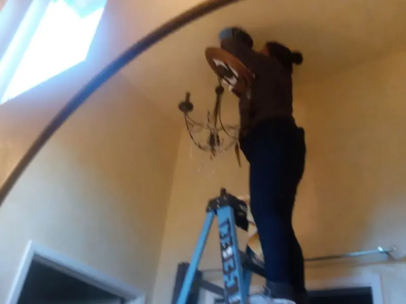 Electrician installing a chandelier in a Newington residence